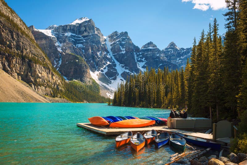 Canoes on a jetty at Moraine lake in Banff National Park, Alberta, Canada, with snow-covered peaks of canadian Rocky Mountains in the background. Canoes on a jetty at Moraine lake in Banff National Park, Alberta, Canada, with snow-covered peaks of canadian Rocky Mountains in the background.