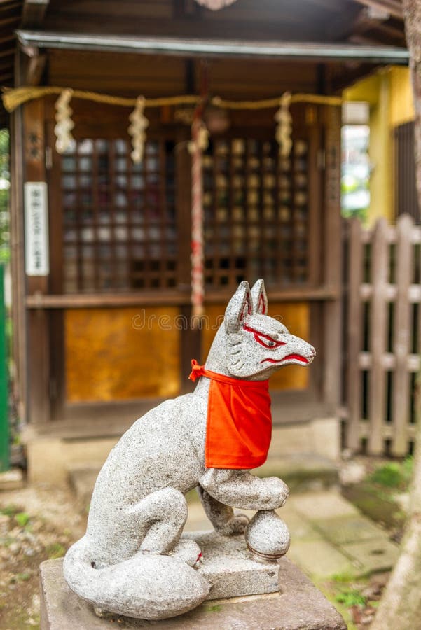 A stone fox in a Shintoist shrine in Tokyo in Summer. A stone fox in a Shintoist shrine in Tokyo in Summer