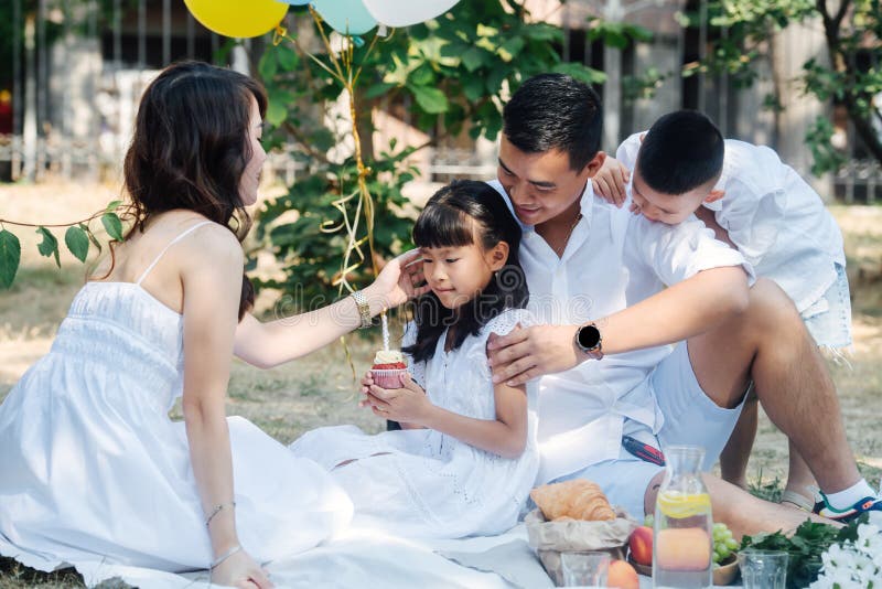 在公园庆祝小女儿生日的亚洲家庭 免版税库存照片