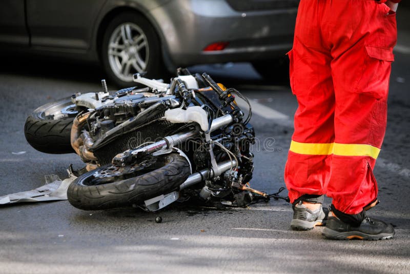 在公路事故以后的被碰撞的摩托车与汽车 库存照片