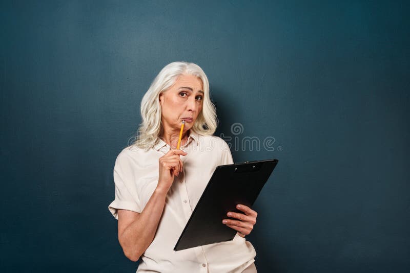 在剪贴板的迷茫的成熟老妇人文字笔记 免版税库存照片