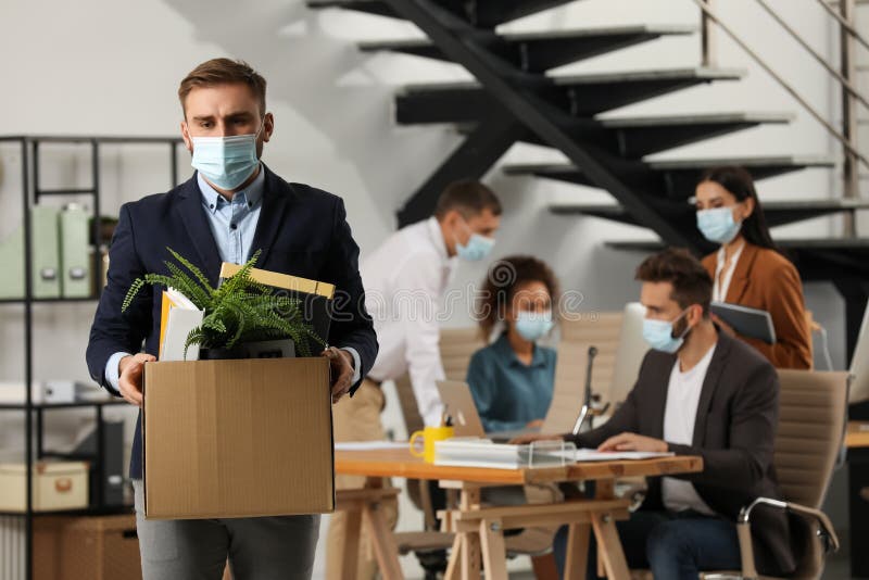 Upset dismissed man carrying box with stuff in office. Upset dismissed man carrying box with stuff in office