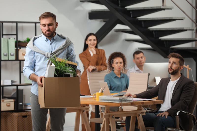 Upset dismissed men carrying box with stuff in office. Upset dismissed men carrying box with stuff in office