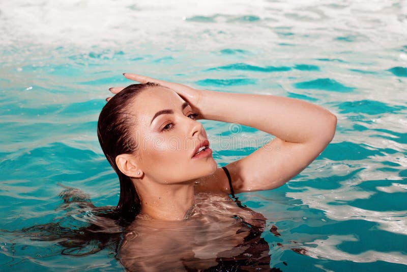 Sexy young beauty swims in the pool alone. Spa and relaxation, luxury hotel. Beautiful woman portrait above the water, close-up. Sexy young beauty swims in the pool alone. Spa and relaxation, luxury hotel. Beautiful woman portrait above the water, close-up.