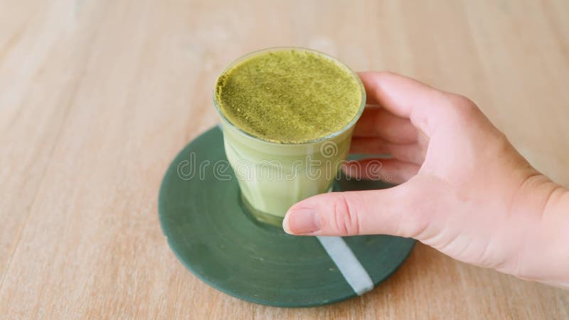 在咖啡店里手拿一杯绿色抹茶拿铁的女孩 影视素材