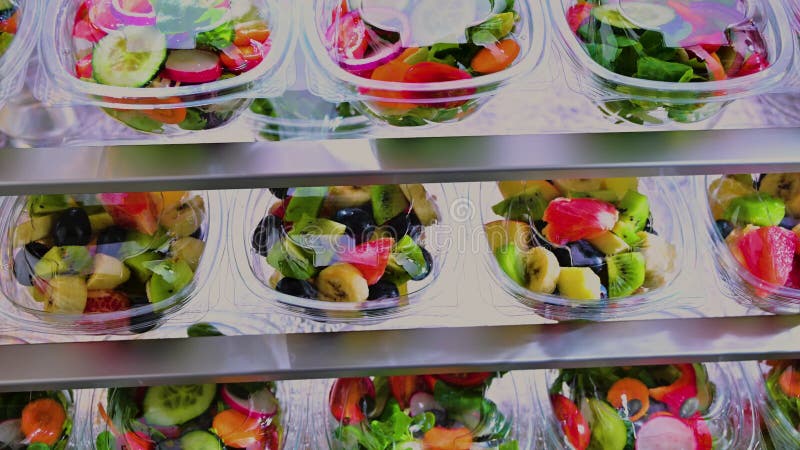 在商用冰箱中出售的塑料盒，内装预包装水果和蔬菜沙拉