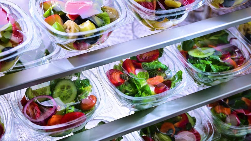 在商用冰箱中出售的塑料盒，内装预包装水果和蔬菜沙拉
