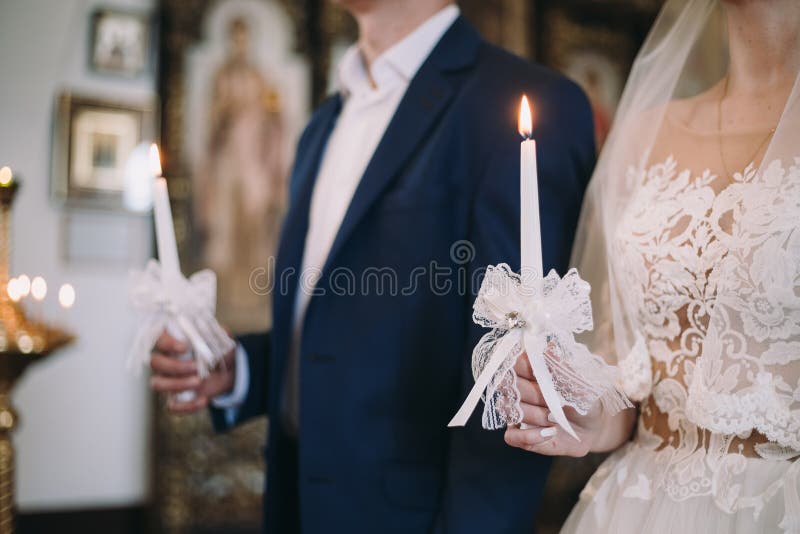 在婚礼的年轻夫妇在他们的手上举一个灼烧的蜡烛 免版税图库摄影 在婚礼的年轻夫妇在他们的手上举一个灼烧的蜡烛 免版税图库摄影