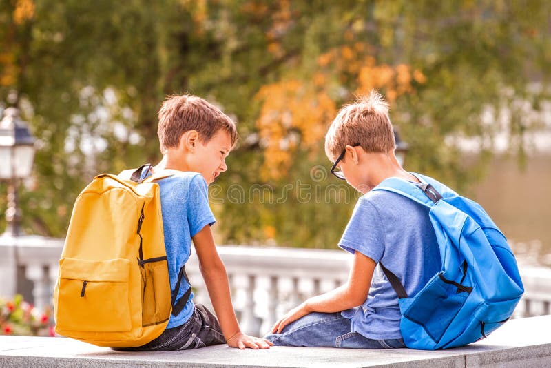 在学校以后的两个男孩，坐长凳和谈话 库存照片