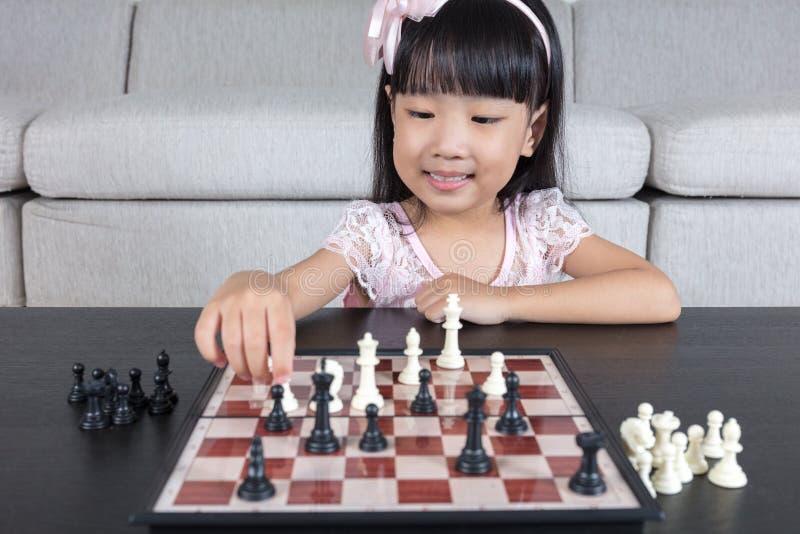 在家下棋棋的愉快的亚裔中国小女孩 免版税库存照片
