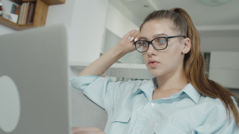 在家使用膝上型计算机的窘迫十几岁的女孩，键入在笔记本，为检查或家庭作业做准备