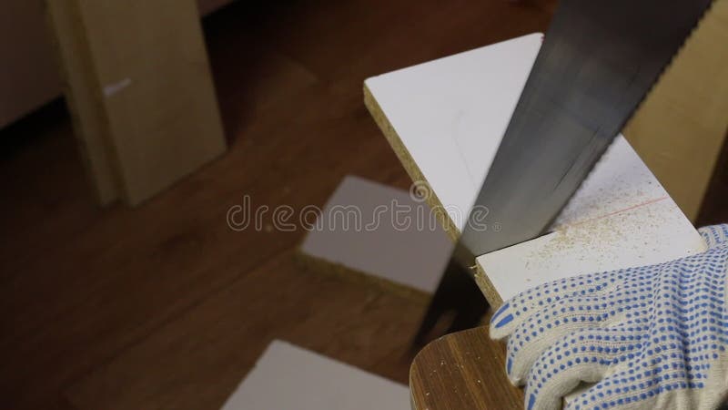 在家做家具. 一个男人用钢锯沿着标线切板