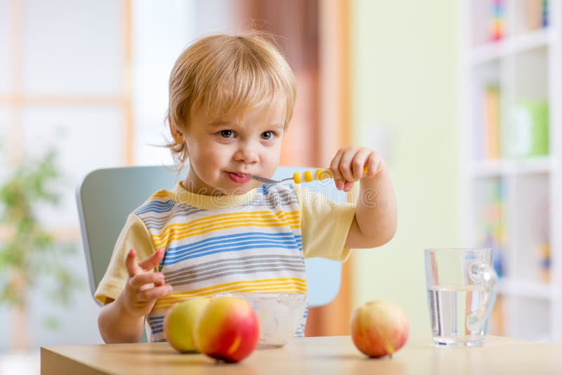 Happy child toddler eating food cheese with fruits at home. Happy child toddler eating food cheese with fruits at home