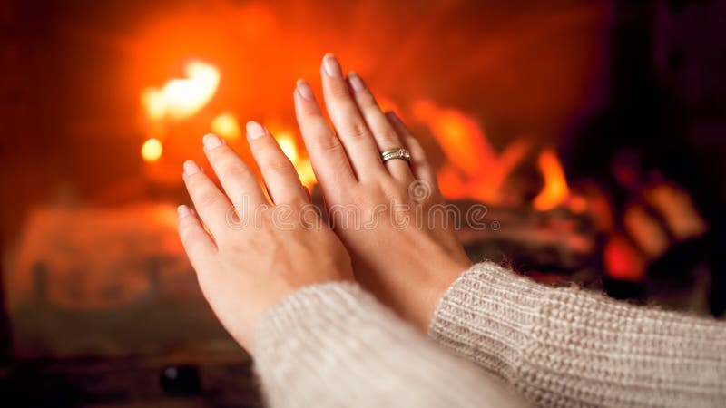在家壁炉前暖手的毛衣女青年特写 免版税库存照片 在家壁炉前暖手的毛衣女青年特写 免版税库存照片