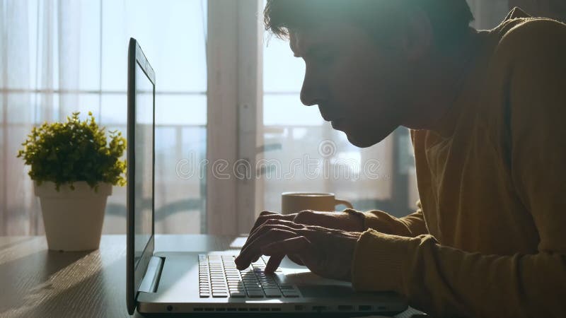 在家工作时，集中注意力在键盘上打字的年轻人. 严肃的男性职业