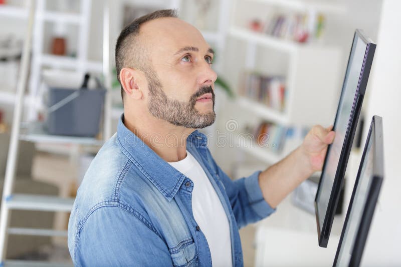 在家挂画框的男子 免版税图库摄影