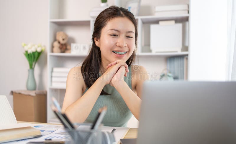 在家课堂上观看教师现场表演或视频通话的亚洲年轻女学生 图库摄影