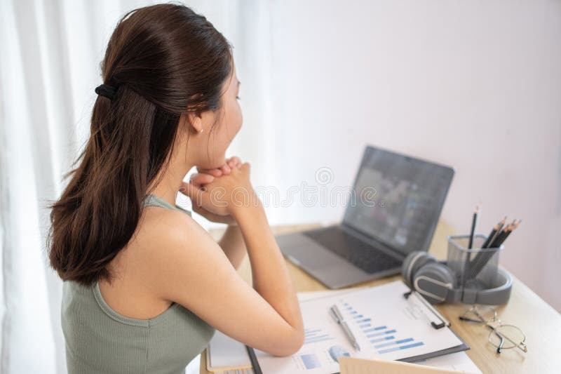 在家课堂上观看教师现场表演或视频通话的亚洲年轻女学生 图库摄影