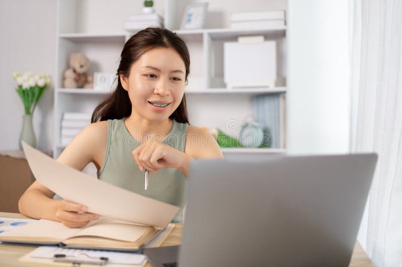 在家课堂上观看教师现场表演或视频通话的亚洲年轻女学生 免版税库存照片