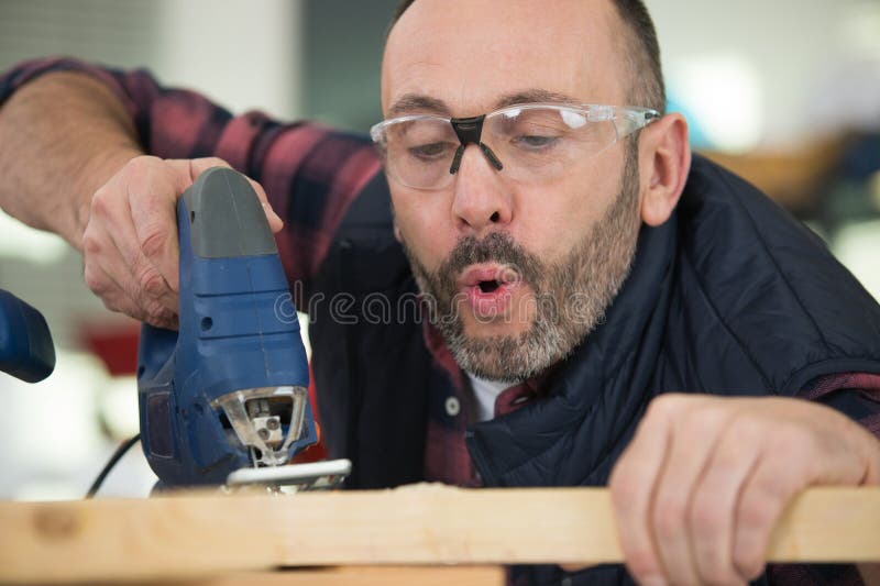 木匠从工作台吹掉锯末，留有复制空间 库存照片