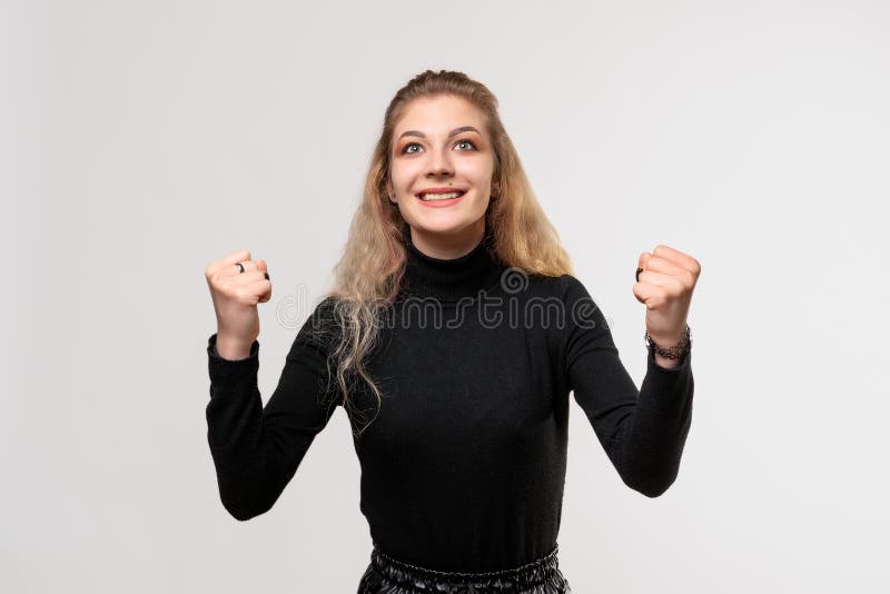 在庆祝成功时，金发女孩欢笑而兴奋 免版税图库摄影
