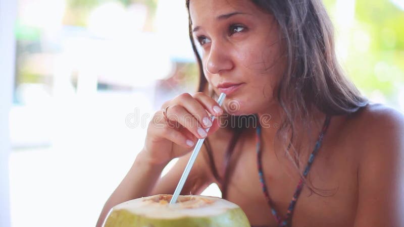 在度假喝从绿色年轻椰子果子的逗人喜爱的年轻深色的妇女新鲜的椰子水 1920x1080