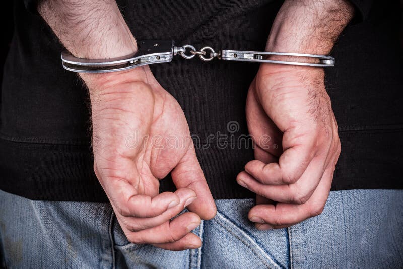 Man hands in handcuffs on wooden background. Man hands in handcuffs on wooden background