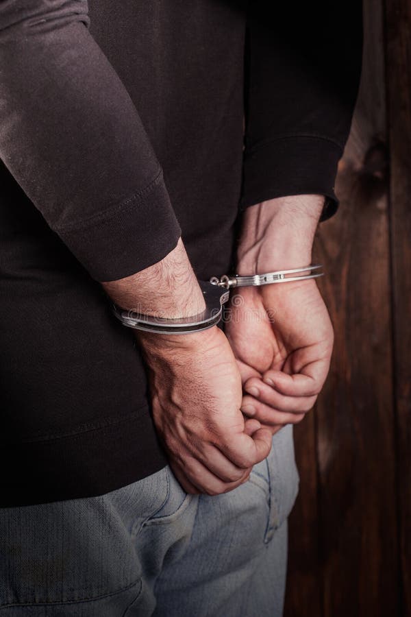 Man hands in handcuffs on wooden background. Man hands in handcuffs on wooden background