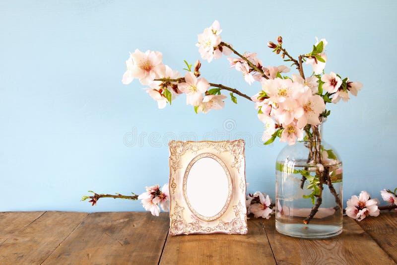 Vintage blank photo frame next to spring white flowers on wooden table. Vintage blank photo frame next to spring white flowers on wooden table