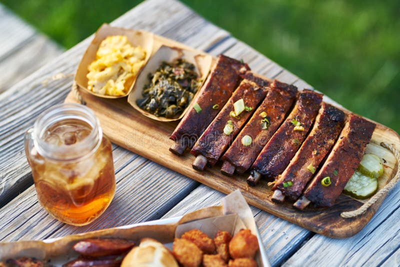 在晴朗的夏日期间,圣路易斯样式与散叶甘兰绿色的bbq肋骨和在野餐桌上的橡皮防水布&乳酪外部 免版税库存照片 在晴朗的夏日期间,圣路易斯样式与散叶甘兰绿色的bbq肋骨和在野餐桌上的橡皮防水布&乳酪外部 免版税库存照片