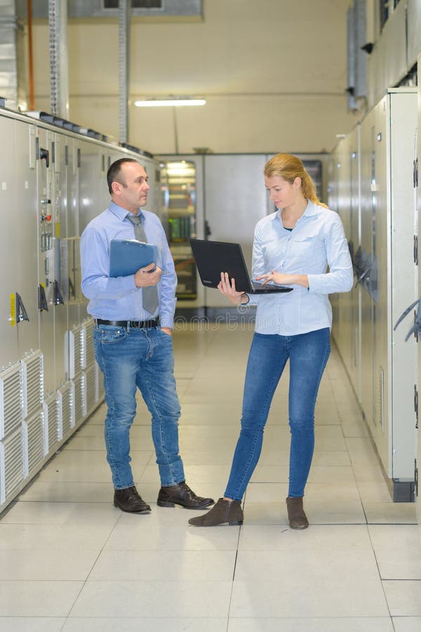 在服务器机房中处理笔记本电脑的技术人员 库存图片