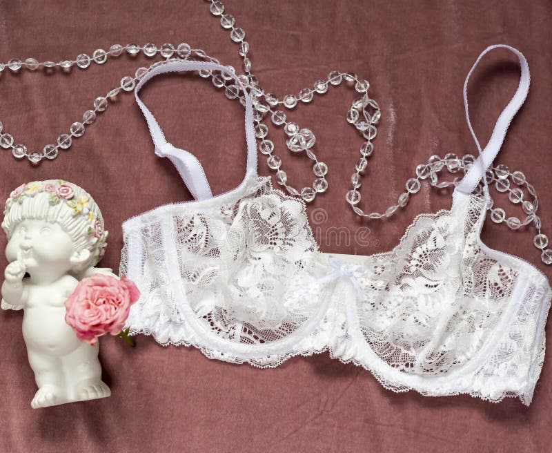 White lace bra on pink velvet background and angel with rose. White lace bra on pink velvet background and angel with rose