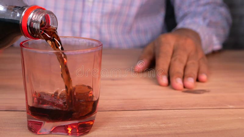 在桌上特写地倒玻璃杯中的软饮料.