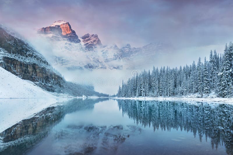 First snow Morning at Moraine Lake in Banff National Park Alberta Canada. Snow-covered winter mountain lake in a winter atmosphere. Beautiful background photo. Most popular place in North America. First snow Morning at Moraine Lake in Banff National Park Alberta Canada. Snow-covered winter mountain lake in a winter atmosphere. Beautiful background photo. Most popular place in North America.