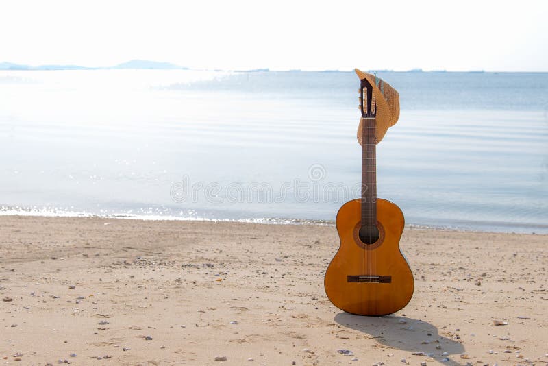 在沙子的夏天移动与吉他的和时尚妇女帽子在假日,日落海滩背景靠岸 库存图片 在沙子的夏天移动与吉他的和时尚妇女帽子在假日,日落海滩背景靠岸 库存图片