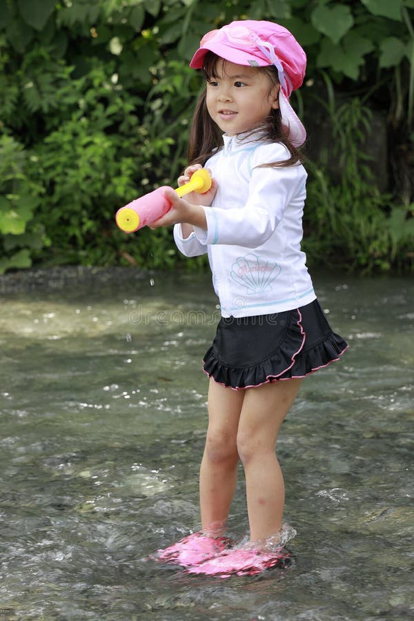 在河里玩水枪的日本女孩 免版税库存图片