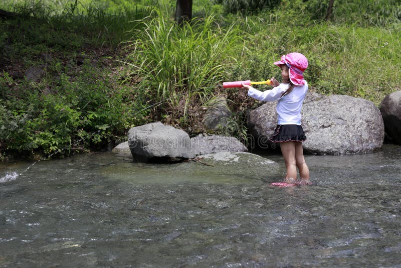 在河里玩水枪的日本女孩 免版税库存照片