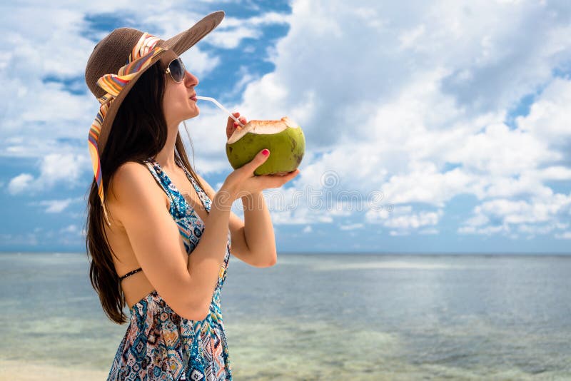 在海滩的妇女旅游饮用的椰奶在假日 图库摄影 在海滩的妇女旅游饮用的椰奶在假日 图库摄影