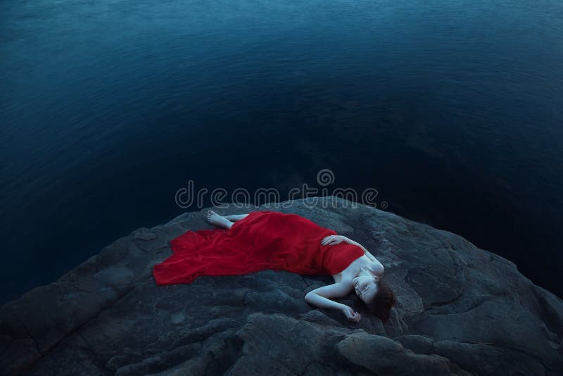 A sad woman in red dress near the sea in evening. Long time exposure. A sad woman in red dress near the sea in evening. Long time exposure