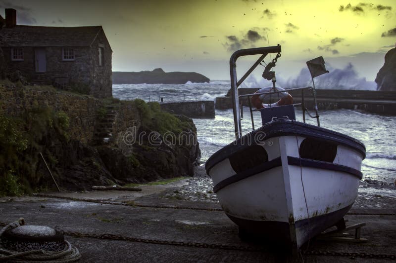 Picture taken of fishing boat in Mullion Cove, Cornwall as the sea crashes in over the harbour wall. Picture taken of fishing boat in Mullion Cove, Cornwall as the sea crashes in over the harbour wall