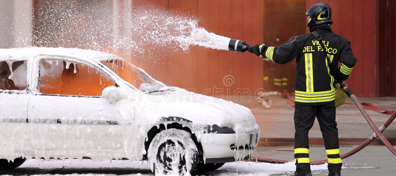 Firemen during exercise to extinguish a fire in a car with foam. Firemen during exercise to extinguish a fire in a car with foam