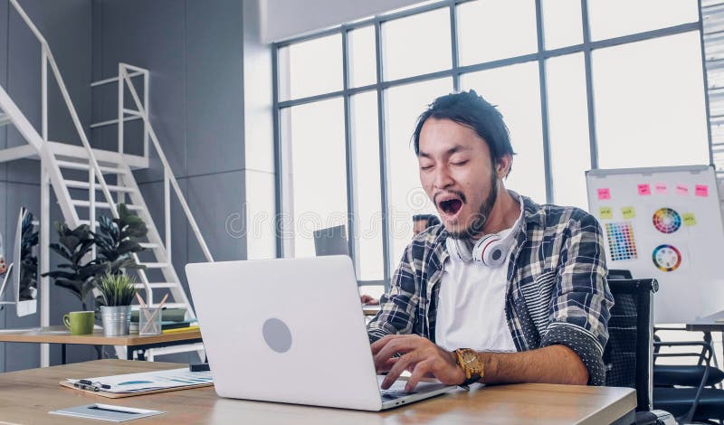 在现代办公室用笔记本电脑辛勤工作、枯燥无趣的创意设计师打哈欠 工作场所寿命概念 免版税图库摄影 在现代办公室用笔记本电脑辛勤工作、枯燥无趣的创意设计师打哈欠 工作场所寿命概念 免版税图库摄影