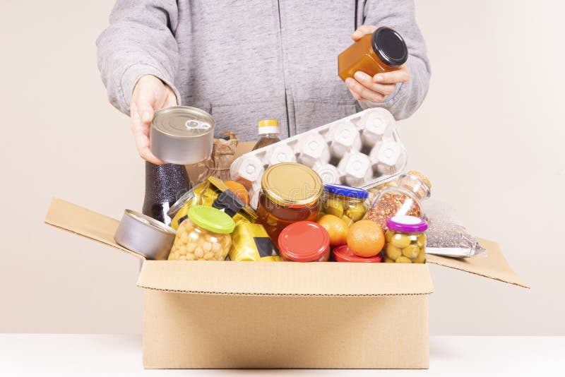 在白桌上摆满食品的食品捐赠盒的志愿者手 库存图片