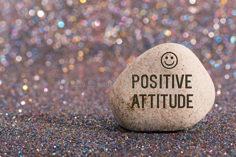 A white stone with words positive attitude and smile face on color glitter boke background. A white stone with words positive attitude and smile face on color glitter boke background