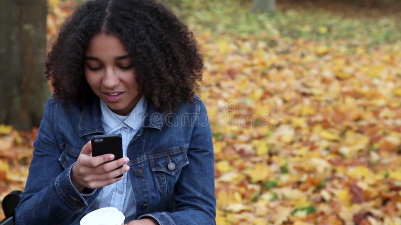 在社交媒体上用手机在户外穿蓝色牛仔夹克的非裔美国少女