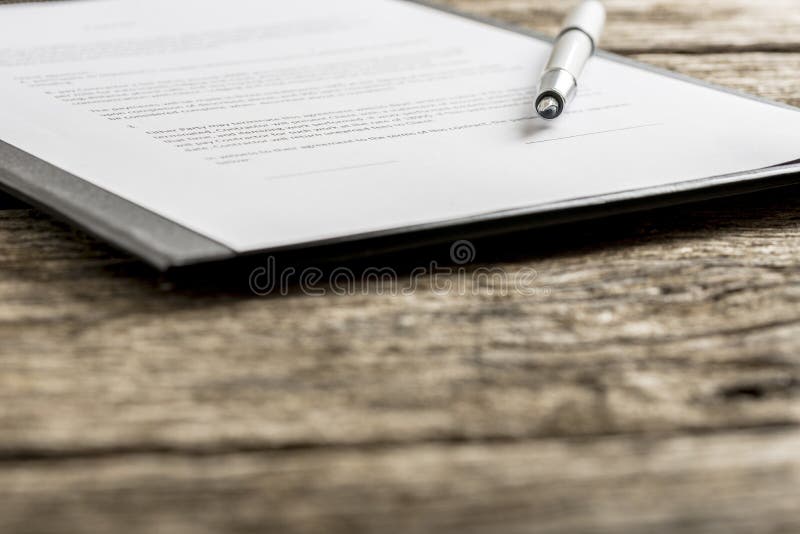 Uncapped pen on top of typewritten piece of paper on clipboard. Includes out of focus foreground with copy space. Uncapped pen on top of typewritten piece of paper on clipboard. Includes out of focus foreground with copy space.