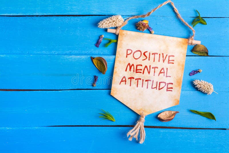 Positive mental attitude text on Paper Scroll with dried flower around and blue wooden background. Positive mental attitude text on Paper Scroll with dried flower around and blue wooden background