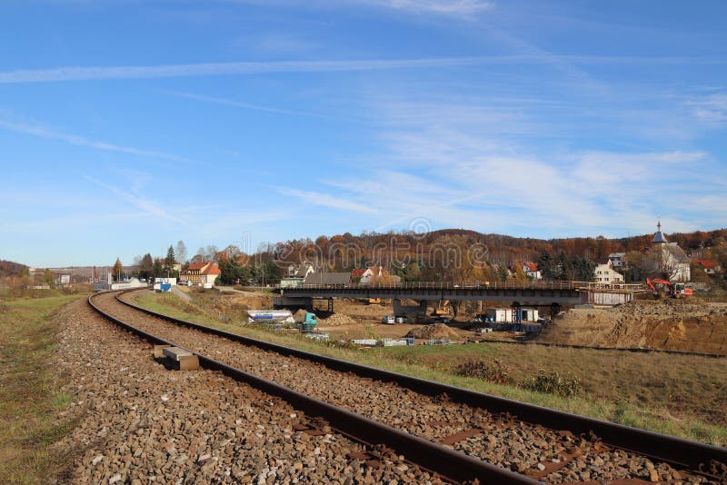 An electrified railway track among green meadows and wheat fields. Building a bridge in a small town. An electrified railway track among green meadows and wheat fields. Building a bridge in a small town