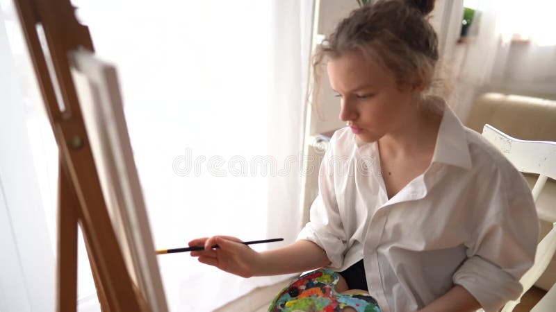 在艺术作坊中画一幅杰作的女画家肖像. 在女孩的侧面画画 股票录像