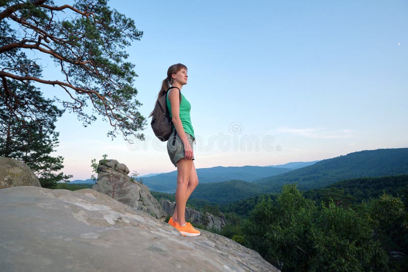 在荒野之路旅行中，徒步登山的女人在山间的人行道上享受夜晚的大自然. 孤独的女性旅行者 库存照片